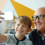 petit fils et son grand père se prennent en photo avec un smarphone