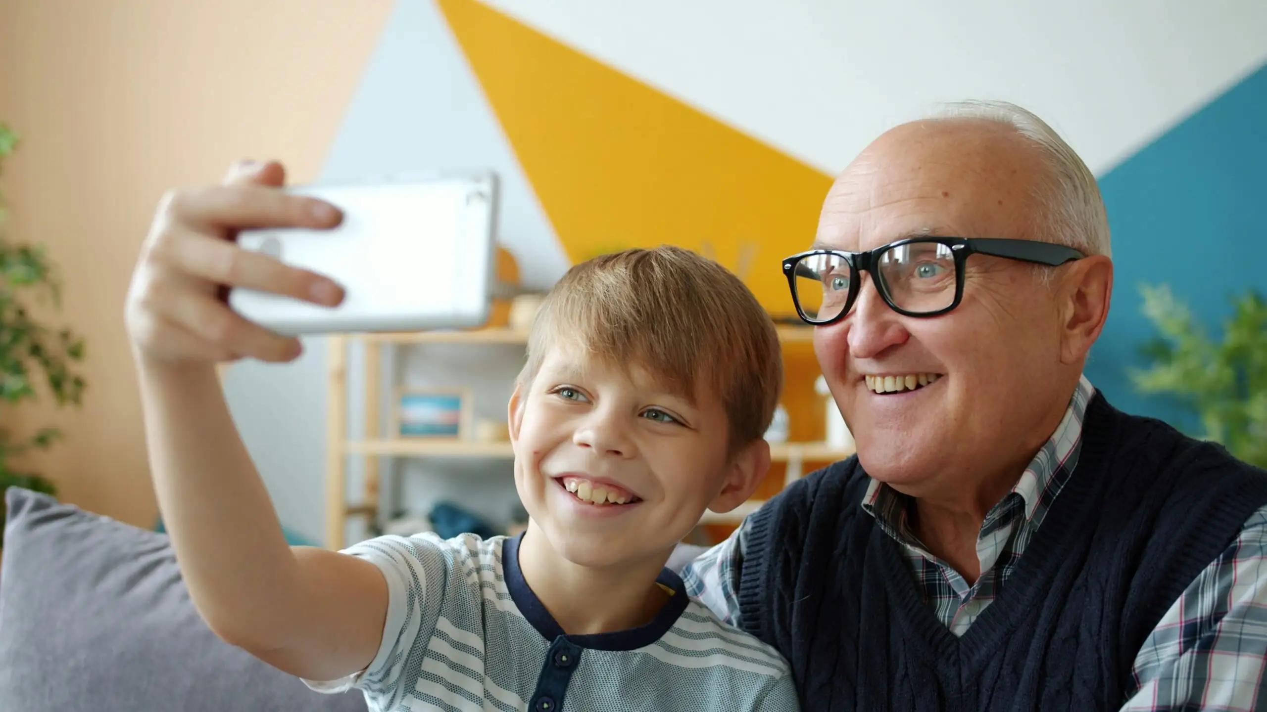 petit fils et son grand père se prennent en photo avec un smarphone