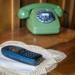 deux anciens téléphones posés sur une petite table en bois