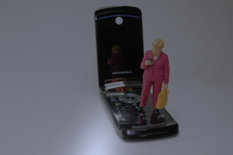 Téléphone mobile noir à claper.Une dame en miniature se tient sur le clavier du téléphone