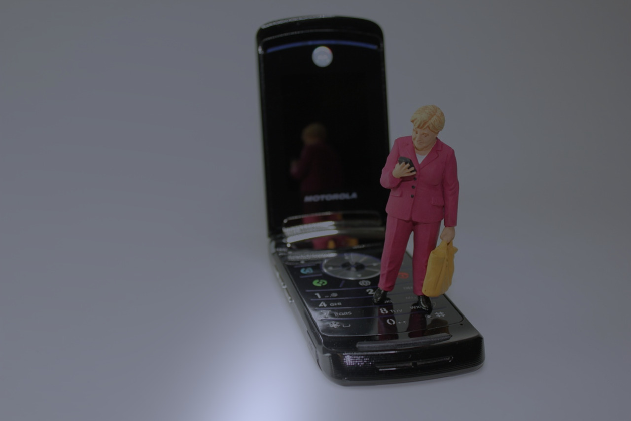 Téléphone mobile noir à claper.Une dame en miniature se tient sur le clavier du téléphone