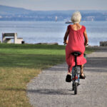 Une femme âgée sur son vélo se dirige vers un lac