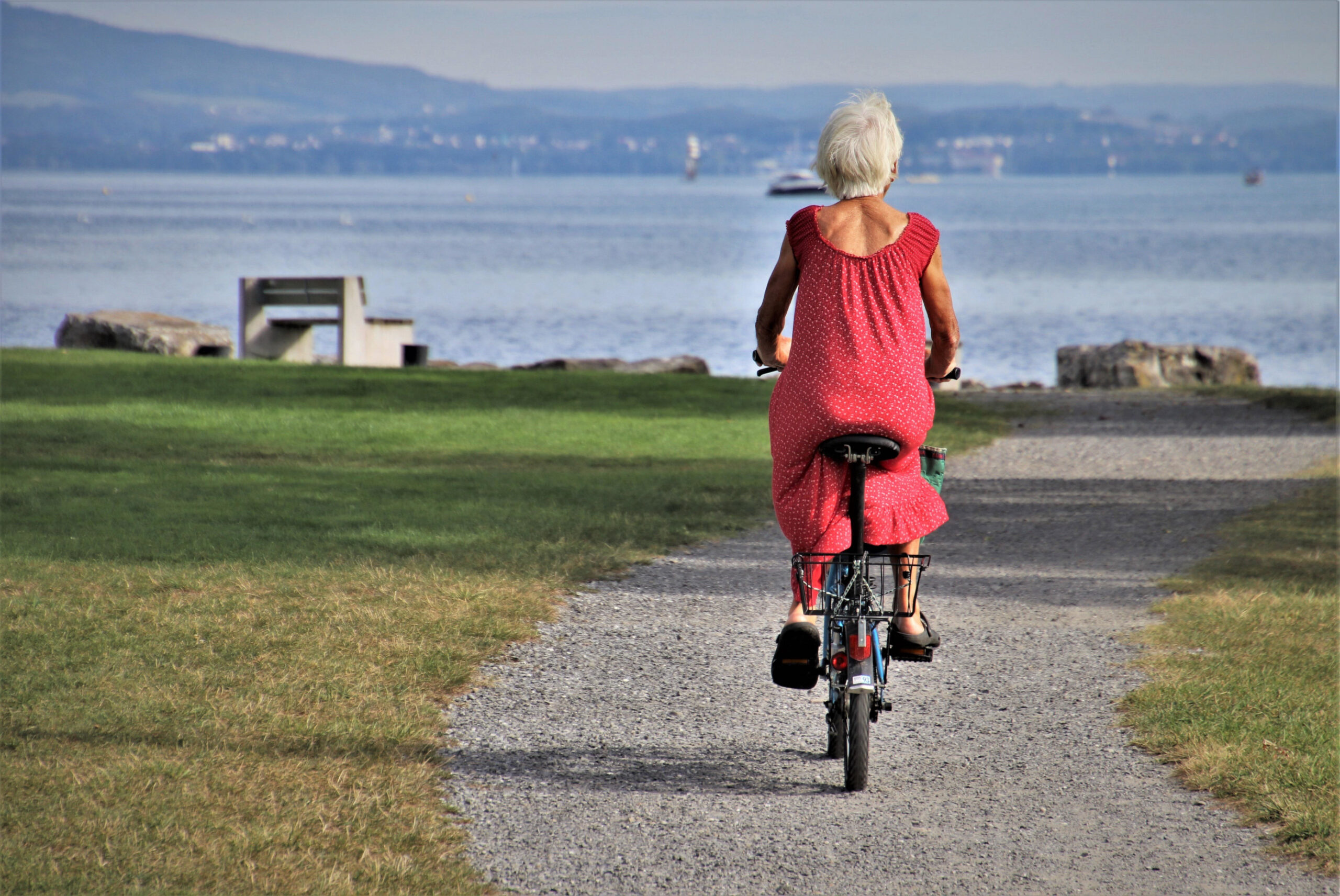 Une femme âgée sur son vélo se dirige vers un lac