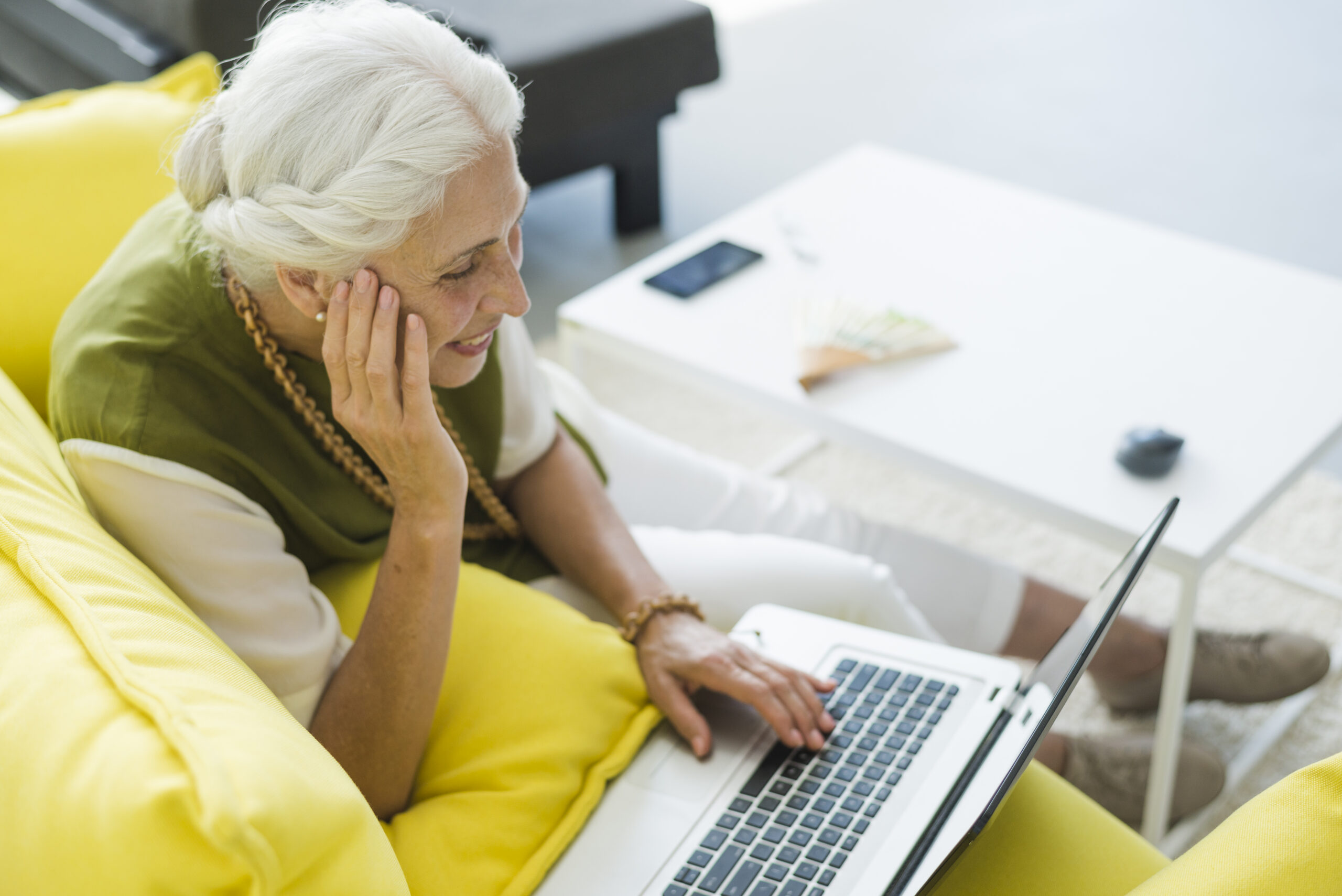 Femme âgée sur son canapé utilise son PC portable