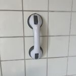 Poignée de sécurité à ventouse sur un mur carrelé.