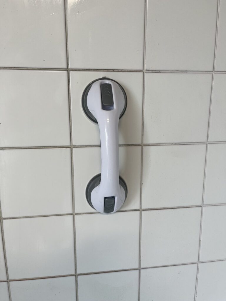 Poignée de sécurité à ventouse sur un mur carrelé.