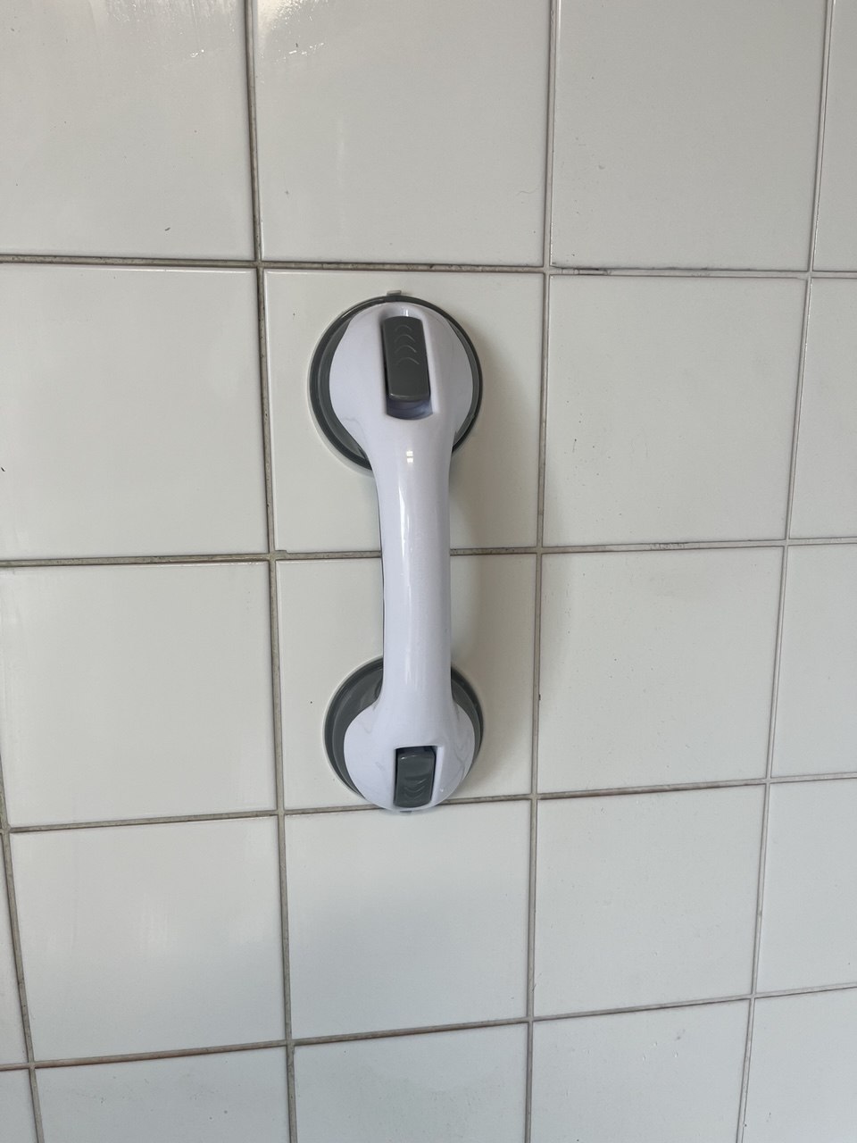 Poignée de sécurité à ventouse sur un mur carrelé.